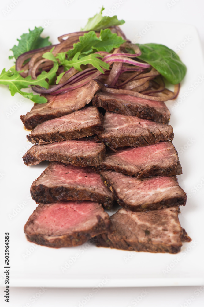 Plate with meat cutting and fresh greens on white plate