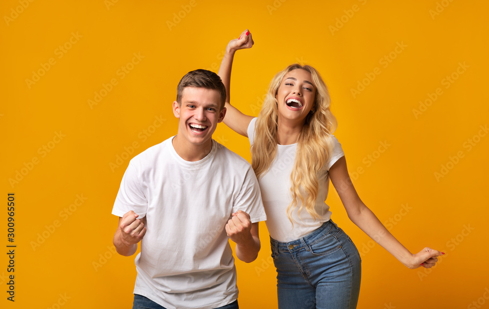 Obraz premium Happy millennial couple celebrating success on yellow background