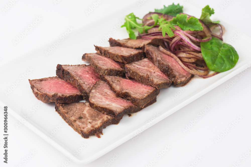 Plate with meat cutting and fresh greens on white plate