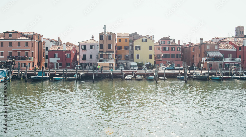 Venice landmark, Burano island canal, colorful houses and small fishing boats, Italy.