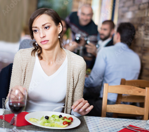 Portrait of upset woman in the restaurant with salad and wine photo