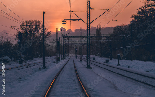 Snow covered empty train tracks at sunset