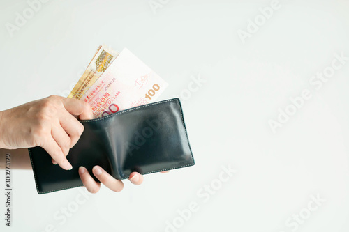 Hands picking Hong Kong money (Dollar Hong Kong or HKD) from short wallet for payment.
