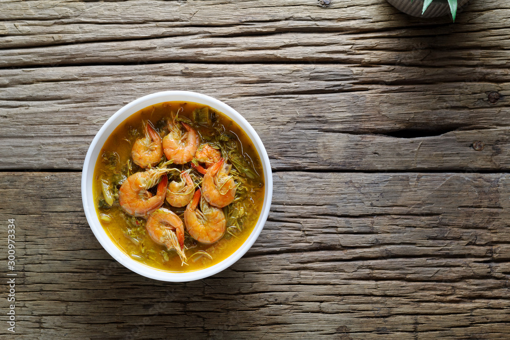 Coconut Milk Curry with young Tamarind Leaves ,morning glory and shrimp in bowl on wood table.Thai traditional food Coconut Milk Curry with young Tamarind Leaves ,morning glory and shrimp in bowl on wood table.Thai traditional food
