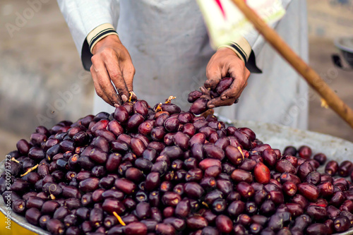 A seller man touches fresh dates on the plate at the bazaar