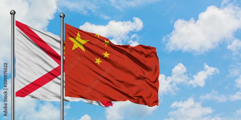 Jersey and China flag waving in the wind against white cloudy blue sky together. Diplomacy concept, international relations.