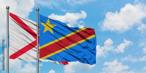 Jersey and Congo flag waving in the wind against white cloudy blue sky together. Diplomacy concept, international relations.