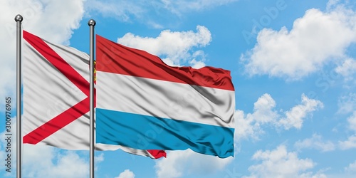 Jersey and Luxembourg flag waving in the wind against white cloudy blue sky together. Diplomacy concept, international relations.