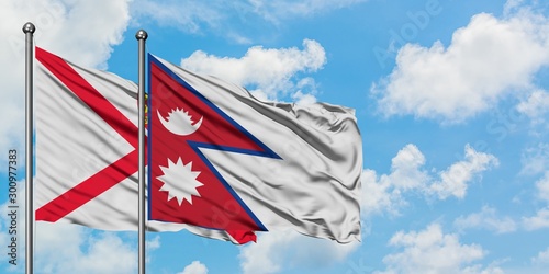 Jersey and Nepal flag waving in the wind against white cloudy blue sky together. Diplomacy concept, international relations.
