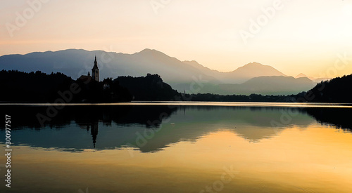 Sunrise at Lake Bled Slovenia and its reflection. Symmetry is the concept. Alps in background. Tower of bell church in the island is visible.