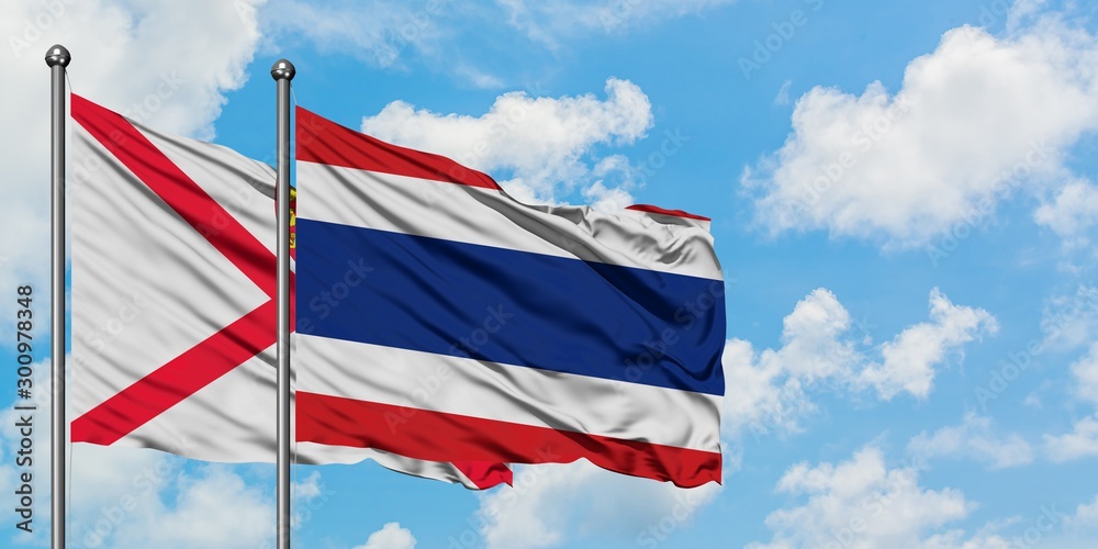 Jersey and Thailand flag waving in the wind against white cloudy blue sky together. Diplomacy concept, international relations.