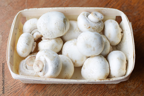 Basket with champignons stands on a wooden table.