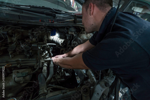 Auto mechanic working on car engine in mechanics garage. Car repair service.