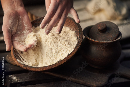 Woman hands kneads dough from flour