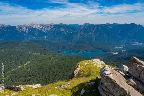 Alpine lake with mountain range and forest landscape on sunny summer day