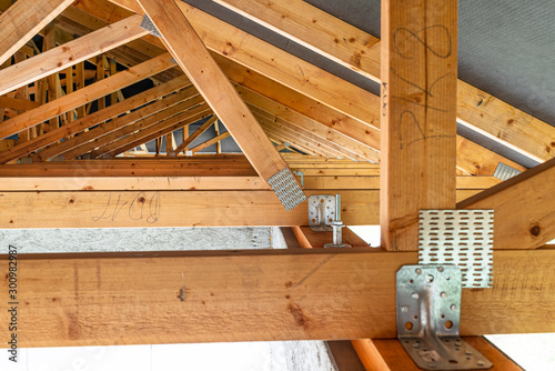 Roof trusses covered with a membrane on a detached house under construction, view from the inside, visible roof elements and truss plates.