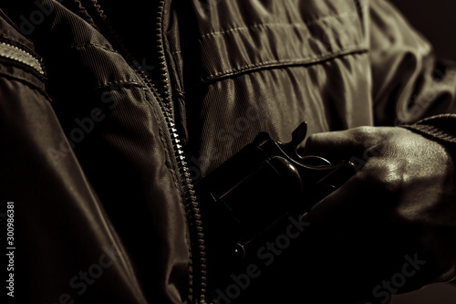 man hide a gun in a jacket in the darkness