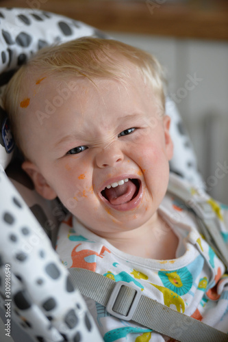 Baby in a highchair with tongue