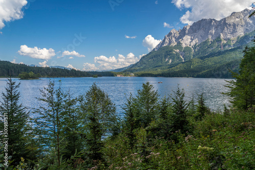Alpine lake with mountain range and forest landscape on sunny summer day