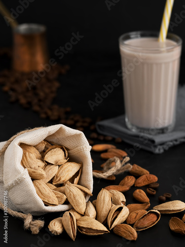 Almond milk with almonds on a black background. Coffee beans and espresso cezve. Close-up. Healthy eating concept. Copy space Natural light. photo