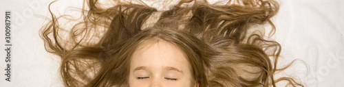 little girl with beautiful long curly hair lies in the bed