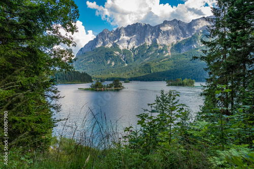 Alpine lake with mountain range and forest landscape on sunny summer day
