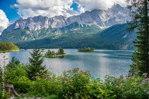 Alpine lake with mountain range and forest landscape on sunny summer day