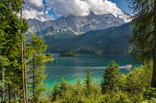 Alpine lake with mountain range and forest landscape on sunny summer day