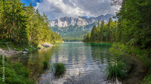 Alpine lake with mountain range and forest landscape on sunny summer day