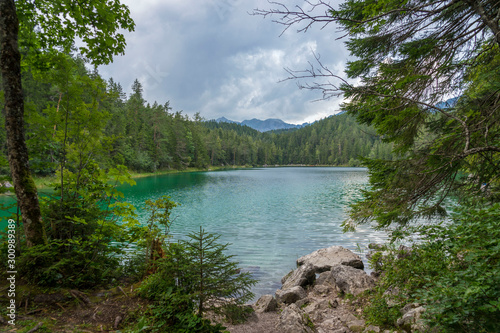 Alpine lake with mountain range and forest landscape on sunny summer day