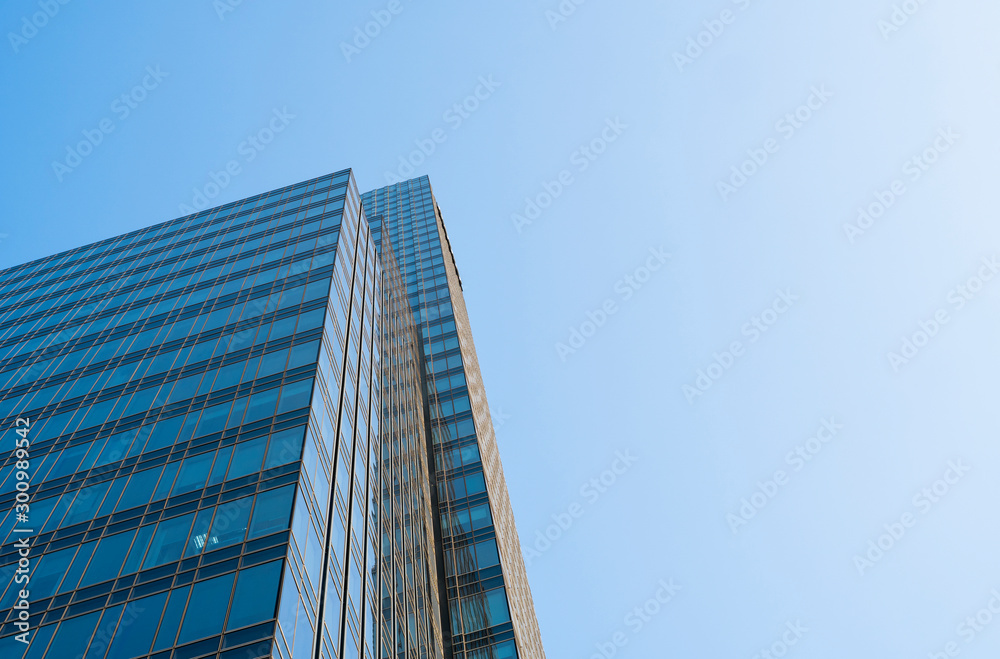 Reflection of the sky in the windows of a building. Perspective and underdite angle view to modern glass building skyscrapers over blue sky. Windows of Bussiness office or corporate building.