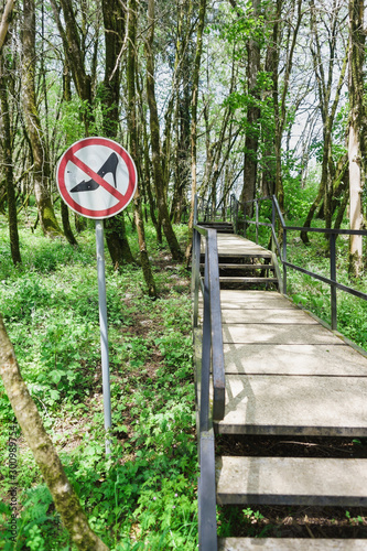 A sign with a ban to continue driving in heels and other uncomfortable shoes on the path of the health Hiking route in the yew-boxwood grove of Khosta district