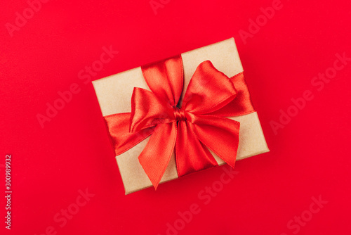 Cardboard gift box with bow on red background. Flat lay. Top view.