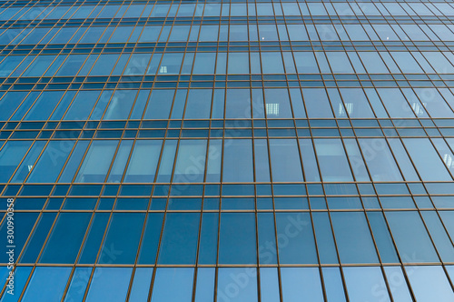 Reflection of the sky in the windows of a building. Perspective and underdite angle view to modern glass building skyscrapers over blue sky. Windows of Bussiness office or corporate building.