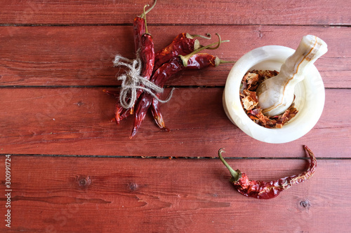 Chili peppers in stone mortar and dried chillies on wooden background.  This condiment could be ingredient of harissa, jika, muhammara or other middle east food. Copy spase.. photo