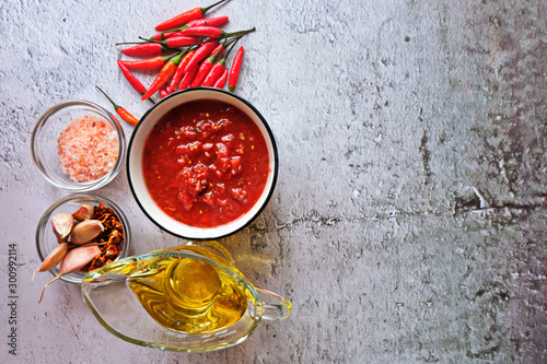 Adjika, hot harissa sauce - spicy hot paste of chilli pepper, tomato on table. Copy spase. photo