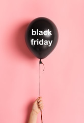 Black friday balloon in woman hand on pink background