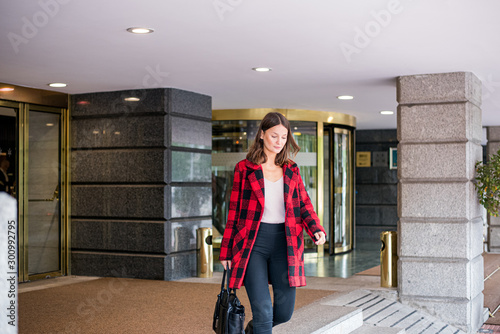 pretty young woman walking leaving an Hotel wearing autumn elegant clothes © DavidPrado