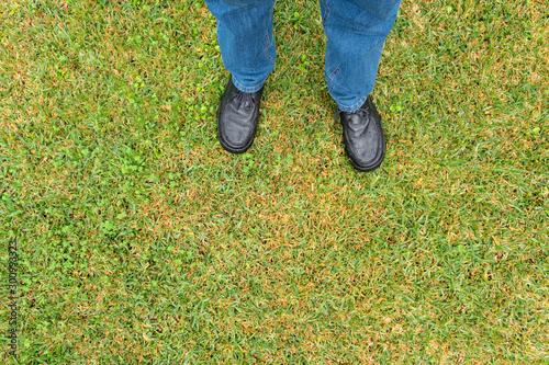 Man legs with pants and black shoes on wet sward