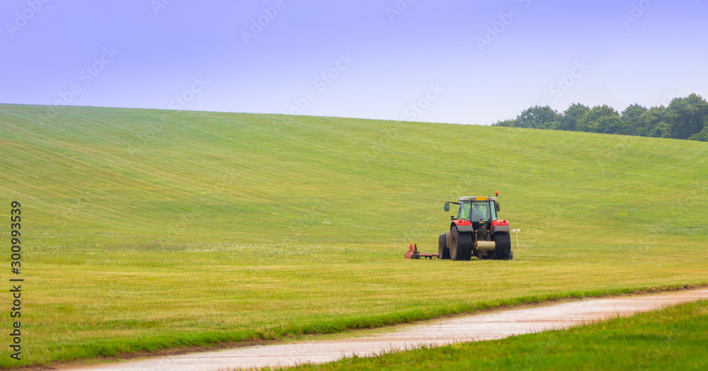 Tractor mower on a green field with blue sky Tractor mower on a green field with blue sky