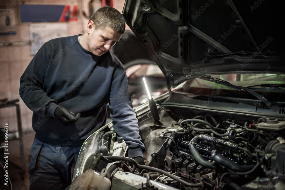 Car mechanic repairer service technician checks and repairs auto engine