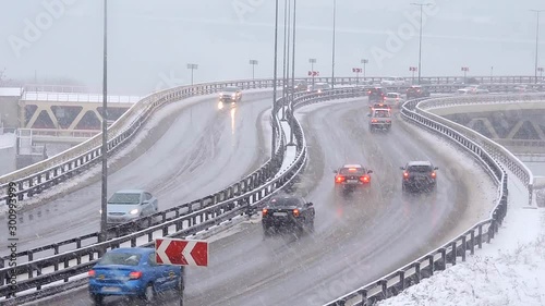 Cars driving on snowy road in winter, traffic on highway in snowfall, blizzard. Snow storm