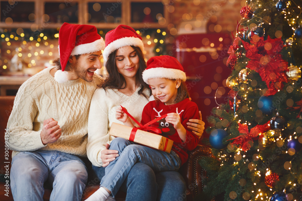 Cute festive girl openng xmas gifts with mom and dad Cute festive girl openng xmas gifts with mom and dad