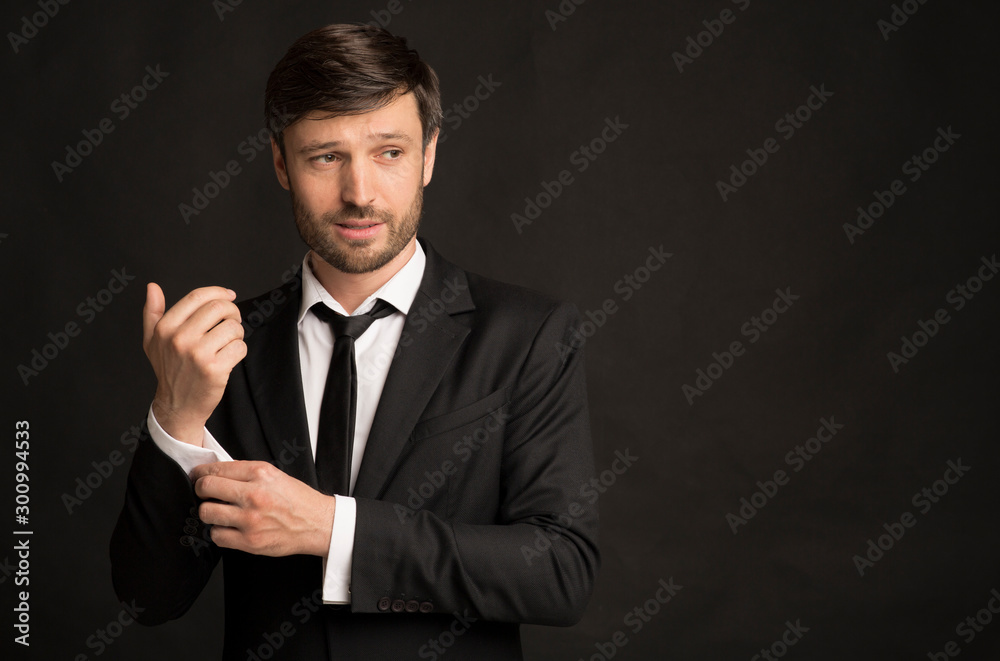 Handsome Businessman In Suit Buttoning Shirt Sleeve Standing In Studio Handsome Businessman In Suit Buttoning Shirt Sleeve Standing In Studio