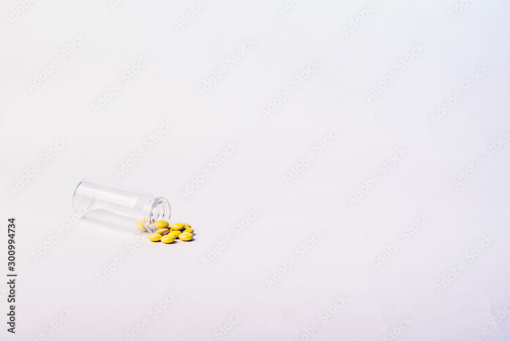 Yellow valerian tablets spilled out of a small glass bottle. Isolate on a white background. Pharmaceutical concept. Yellow valerian tablets spilled out of a small glass bottle. Isolate on a white background. Pharmaceutical concept.