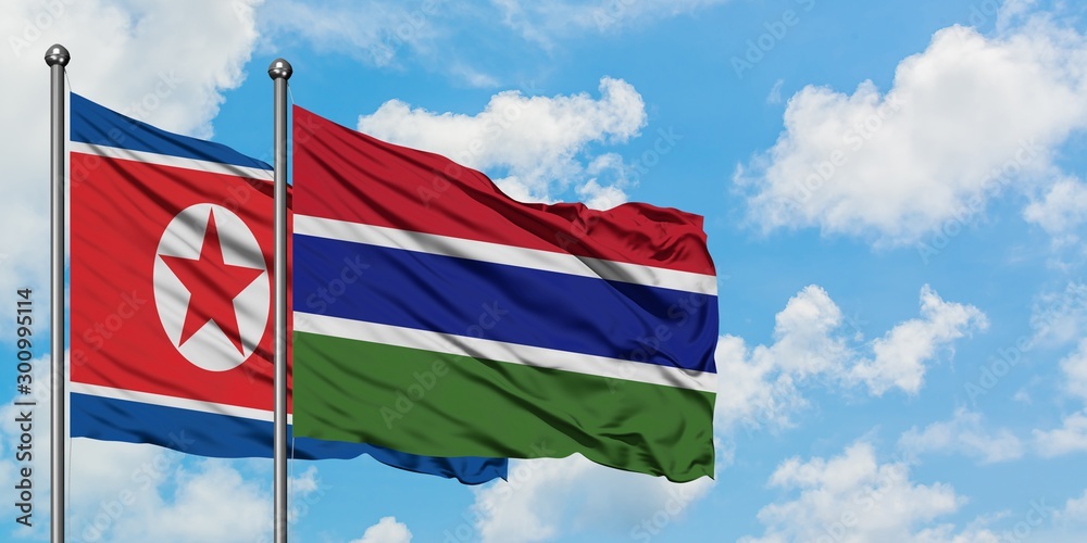 North Korea and Gambia flag waving in the wind against white cloudy blue sky together. Diplomacy concept, international relations. North Korea and Gambia flag waving in the wind against white cloudy blue sky together. Diplomacy concept, international relations.