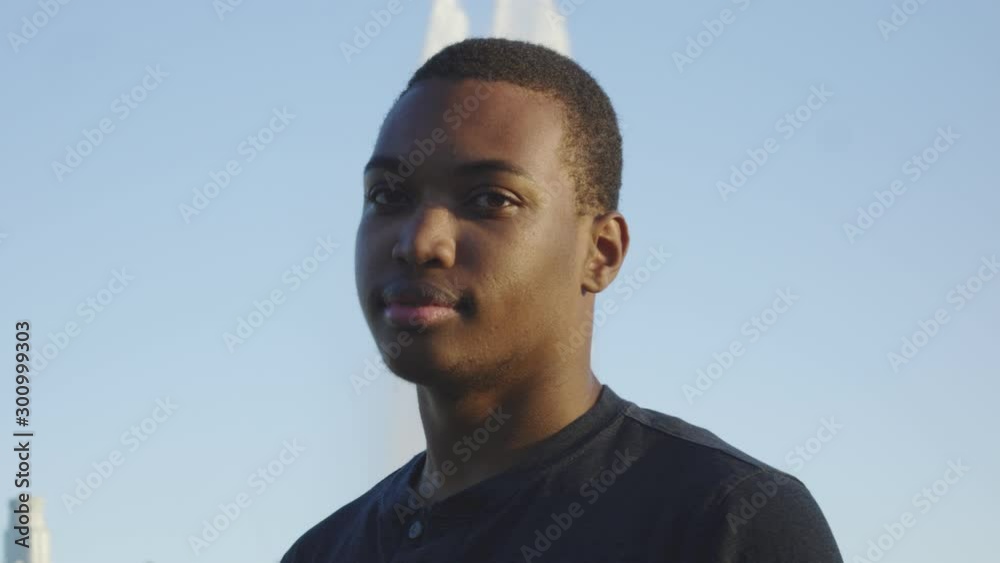 Young african american man looking at camera as it moves around him Young african american man looking at camera as it moves around him