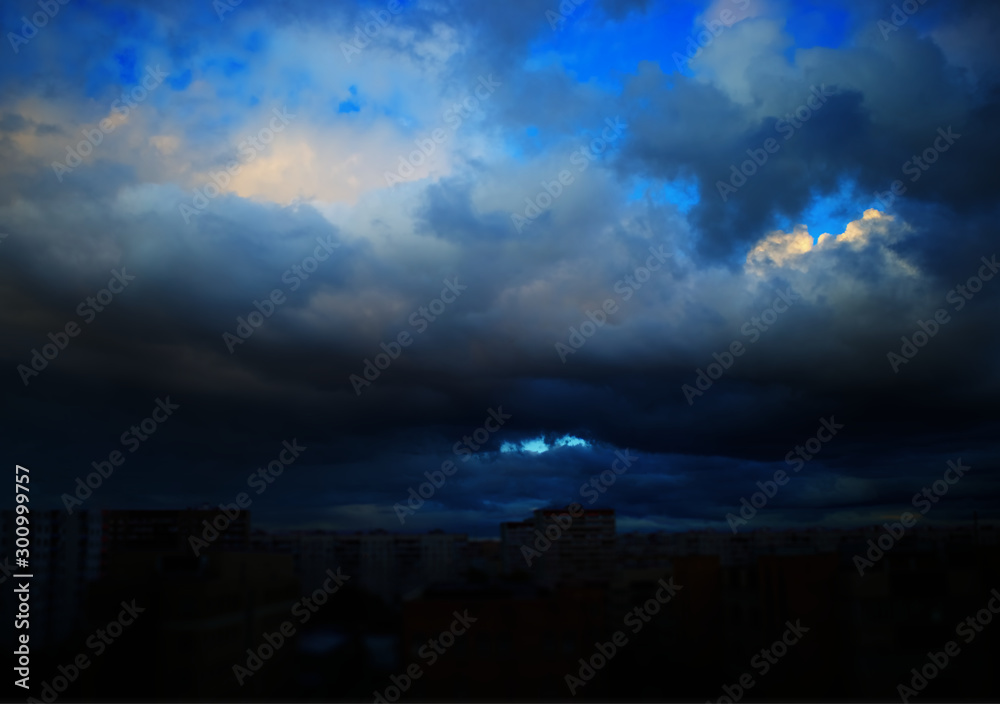 Dramatic clouds covering dark blurred city background