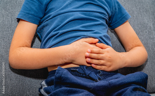 Abdominal pain in a child. Health and pharmaceutical concept, child health problems. The child is holding his stomach, indigestion, the virus attacks the stomach.