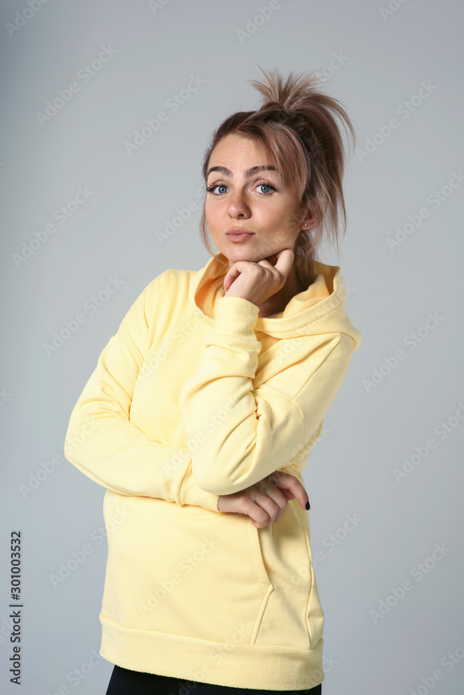 Close up of young attractive caucasian woman in yellow hoodies looking at camera posing funny, shocked with expression. Positive emotions of girl. Model tests on white background Close up of young attractive caucasian woman in yellow hoodies looking at camera posing funny, shocked with expression. Positive emotions of girl. Model tests on white background